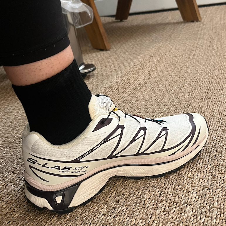 Running shoe positioned on a leg wearing black socks.