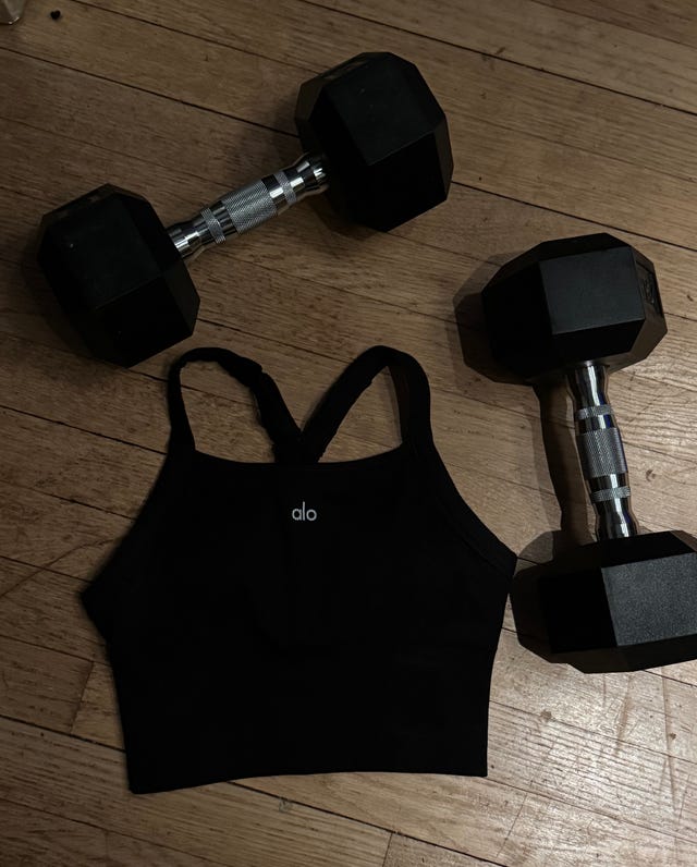 Black sports bra with dumbbells on a wooden floor. Black sports bra with dumbbells on a wooden floor.
