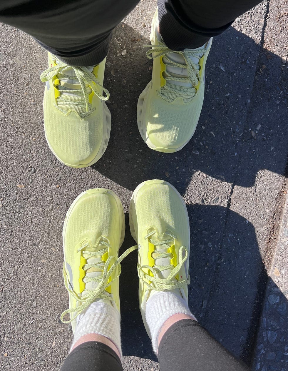 Two pairs of yellow sneakers on a sidewalk.