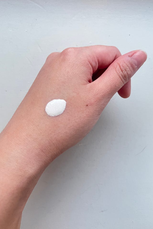 Mano aplicando una sustancia blanca en la piel.