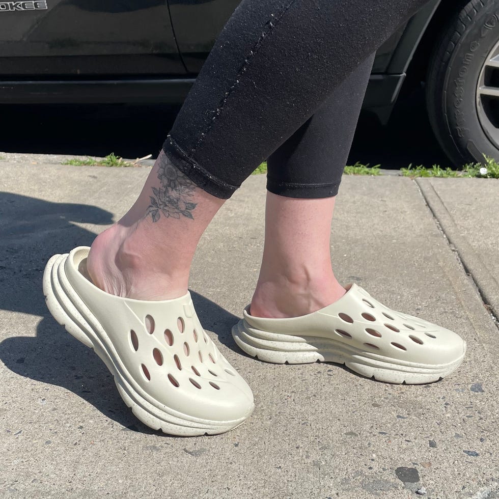 Footwear worn on a sidewalk near a parked black SUV.